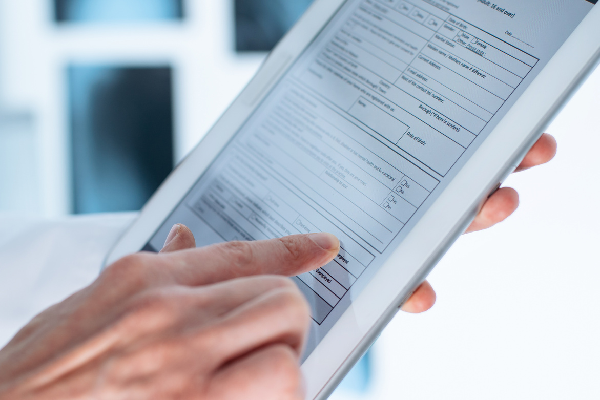 doctor is filling out a patient registration form on a digital tablet